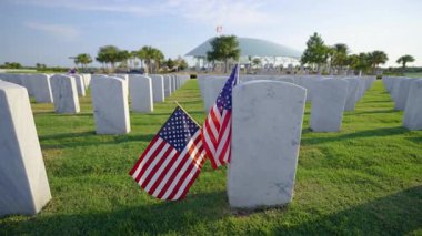 Beyaz mezar taşları ve yeşil çimlerin üzerinde Amerikan bayrağı olan Amerikan ulusal mezarlığı. Anma Günü konsepti