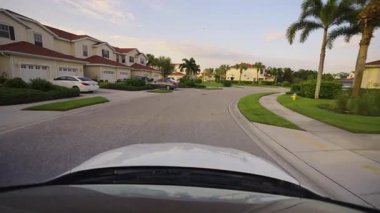 Araba bakış açısı. Florida yerleşim bölgesindeki apartmanlar arasında banliyö sokağında araç sürüyor. Ulaşım ve trafik kavramı