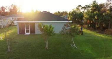 Yazın çim biçme işçisi sıfır çim biçme makinesiyle çim biçiyor. Kırsal kesimin arka bahçesini düzenlemek