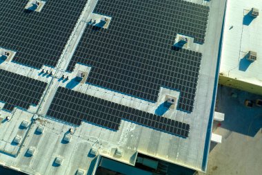 Sanayi binasının çatısına yeşil ekolojik elektrik üretmek için monte edilen mavi fotovoltaik güneş panellerinin hava görüntüsü. Sürdürülebilir enerji konsepti üretimi.