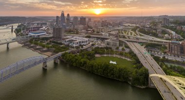 Cincinnati City, Ohio 'daki Daniel Carter Köprüsü şehir merkezinde otoyol trafiği olan araçlarla. Gün batımında ışıl ışıl parlayan yüksek ticari binalarla Amerikan şehri silueti.