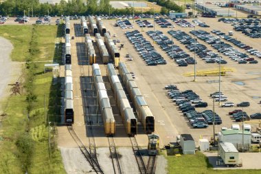 Otomotiv fabrikasının otoparkındaki kargo treni taşıyıcısında yeni arabalar satışa hazır. İthalat ve ihracat için krupiye araç envanteri.