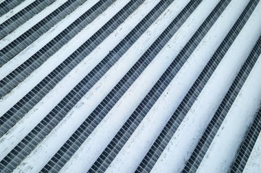 Aerial view of electrical power plant with solar panels covered with snow melting down in winter end for producing clean energy. Concept of low effectivity of renewable electricity in northern region.