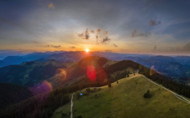Yamaçtaki eski köylü evi. İnanılmaz bir dağ manzarası. Vahşi Ulusal Park Dağları 'nda parlak renkli gün batımı. Sarı batan güneşle aydınlatılmış koyu ladin ormanları..