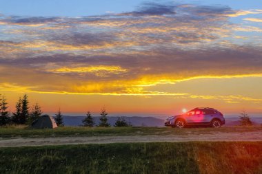 Parlak güneşli bir akşamda kamp alanında turist kampı çadırları ve off-road vagonları. Aktif turizm ve off-road macera konsepti.