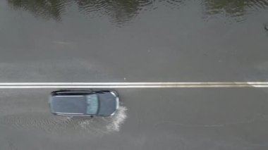 Şiddetli yağmurdan sonra sel basmış caddede giden arabalarla şehir trafiğinin hava görüntüsü. Yol drenaj sistemi ile ilgili sorunlar.