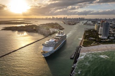 Büyük yolcu gemisi Miami limanında ana kanaldan ayrılıyor. South Beach yakınlarındaki lüks oteller ve apartmanlar..
