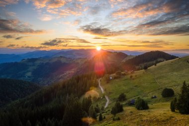 Vahşi dağlardaki renkli günbatımında çobanların eski ahşap kulübelerinin havadan görünüşü. Parlak batan güneşle aydınlanan karanlık çam ormanı. Güzel doğa manzarası.
