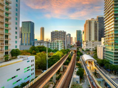 Miami, Florida 'daki Brickell bölgesinde yükseltilmiş tren sistemi. Şehir gökdelenleri ve günbatımı gökyüzü toplu taşıma ağını aydınlatıyor..