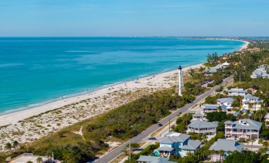 Florida 'nın güneybatısındaki Boca Grande adasındaki yeşil palmiye ağaçları arasında pahalı malikaneler. Ticari gemiler için deniz kıyısındaki beyaz deniz feneri..