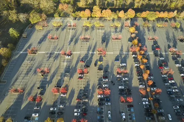 Bir alışveriş merkezinin önündeki otoparkta park edilmiş birçok arabanın üst görüntüsü. Tüketim ve piyasa ekonomisi kavramı.