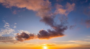 Parlak günbatımı, parlak turuncu ve sarı bulutların ardında batan güneş..