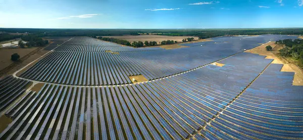 Temiz elektrik enerjisi üretmek için sıra sıra güneş fotovoltaik panelleri olan sürdürülebilir büyük elektrik santralinin havadan görünüşü. Sıfır emisyonlu yenilenebilir elektrik kavramı.