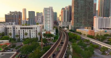 Florida, ABD 'de Miami Brickell' in kalbinden geçen tren rayları ve demiryolu hattı finans bölgesinin günbatımı aydınlatmalı gökdelenleriyle çevrili.