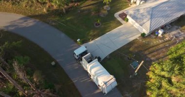 Haftalık temizlik için. Çöp kamyonu Amerikan banliyösündeki kaldırımdan çöp kutuları topluyor.