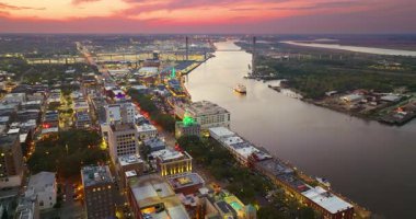 Savannah, Georgia 'daki eski tarihi mimariyle River Street yakınlarında yelken açan Savannah Riverboat ile panoramik şehir manzarası. Günbatımında Güney Amerika mimarisi