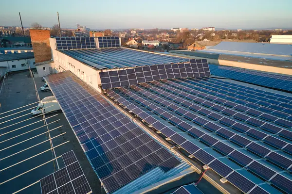 Sanayi binasının çatısına yeşil ekolojik elektrik üretmek için monte edilen mavi fotovoltaik güneş panellerinin hava görüntüsü. Sürdürülebilir enerji konsepti üretimi.