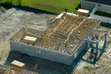 Florida 'nın banliyö bölgesinde inşaat halindeki ahşap çatı iskeleti yapısı olan bitmemiş bir ev üzerinde çalışan inşaatçıların hava görüntüsü..