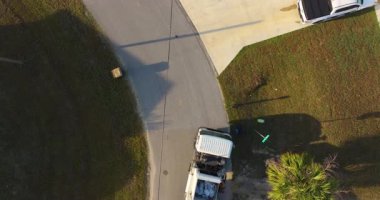 Çöp kamyonu Amerikan mahallesinin kaldırımından çöp kutusu yüklüyor.