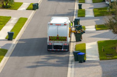 Yerleşim bölgesinde çöp temizleme. Atık kamyonlar banliyö sokaklarında sürerken çöpleri yüklüyorlar.