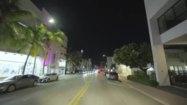 Araba bakış açısı. Miami Beach, Florida 'da gece yarısı şehir sokağında araba sürüyor. Ulaşım ve trafik kavramı