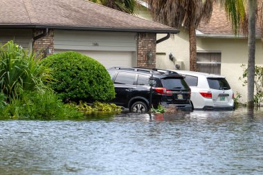 Kasırga yağmuru yolu sular altında bıraktı. Florida yerleşim bölgesinde, şehir caddesinde boğulan arabalar. Kasırga doğal felaketinin sonuçları..