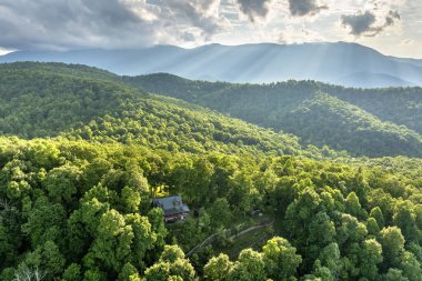 Kuzey Carolina Appalachian dağlarında doğan parlak güneşle aydınlanan dağ gündoğumu ormanındaki ücra bir ev. ABD 'nin seyahat merkezi olarak turizm sığınağı.