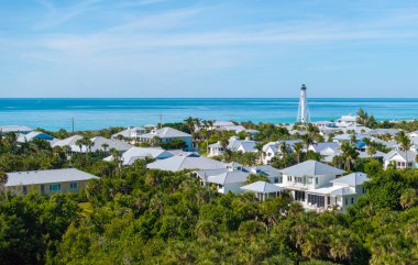 Rich neighborhood with expensive vacation homes and white lighthouse on ocean shore in Boca Grande, small town on Gasparilla Island in southwest Florida. Wealthy waterfront residential area.
