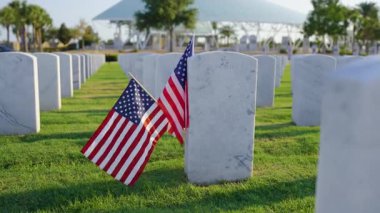 Amerikan ordusu Sarasota Ulusal Mezarlığı 'nda beyaz mezar taşları ve Amerikan bayrağı yeşil çimlerde. Anma Günü konsepti