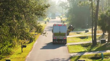 Amerikan mahallesindeki çöp bidonlarını toplayan çöp kamyonu temiz ve organize banliyö bölgesinde düzenli atık yönetiminin bir parçası.