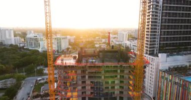 Miami kentsel bölgesinde gayrimenkul geliştirme. Gün batımında yüksek konutlu inşaat alanındaki vinçleri kaldırmak.