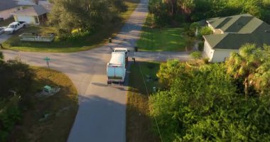 Çöp kamyonu banliyödeki çöp kutularını topluyor.