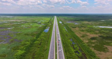 Florida 'daki Gainesville yakınlarında uzun düz otoban. Hızlı giden araçlar açık bataklık ve açık gökyüzü tarafından çevrelenmiş.