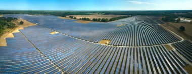 Temiz elektrik enerjisi üretmek için birçok sıra güneş fotovoltaik paneli bulunan sürdürülebilir büyük elektrik santralinin havadan görünüşü. Sıfır emisyon kavramı ile yenilenebilir elektrik.