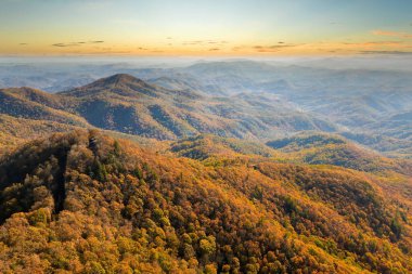 Sonbaharda günbatımında sarı gölgelikleri olan renkli dağ ormanları. Sonbahar mevsiminde vahşi orman manzarası.