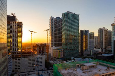 Miami kentsel bölgesinde gayrimenkul geliştirme. Gün batımında yüksek konutlu inşaat alanındaki vinçleri kaldırmak.