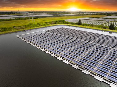 Yüzen fotovoltaik enerji santralinin üzerinden temiz elektrik enerjisi üretmek için birçok sıra güneş paneli görüntülenebilir. Su yüzeyinde hava kirliliği olmayan yenilenebilir elektrik kavramı.