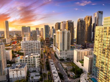 Miami, Florida 'daki Brickell bölgesinde yükseltilmiş tren sistemi. Şehir gökdelenleri ve günbatımı gökyüzü toplu taşıma ağını aydınlatıyor..