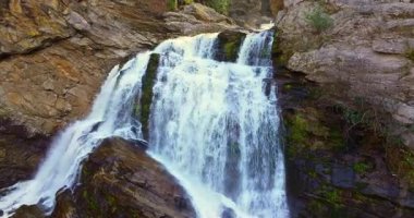 Cullasaja Şelalesi 'nin sonbahar manzarası. Şelale gibi akan sular, dalgalı sarı ve turuncu orman ağaçları arasında engebeli kayaların üzerine dökülüyor..