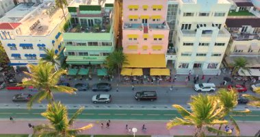 Günbatımında Miami Sahili 'nde renkli Ocean Drive boyunca gezinen turistler. Florida 'nın en çok fotoğraflanan sokağı