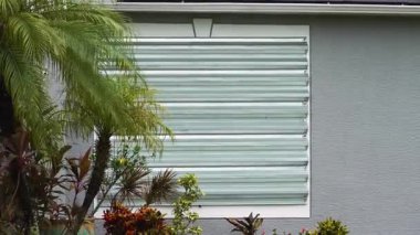 Kasırga panjurlu Florida evi fırtına güvenliği için pencereleri kapatmış. Beklenen doğal afetten önce koruyucu biniş.