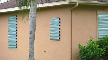Kasırga panjurlu Florida evi fırtına güvenliği için pencereleri kapatmış. Beklenen doğal afetten önce koruyucu biniş.