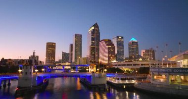 Tampa, Florida. Otoyol köprüsü ve şehir merkezindeki yüksek gökdelen binalarında araba trafiği var. Akşamları finans bölgesi olan Amerikan şehri