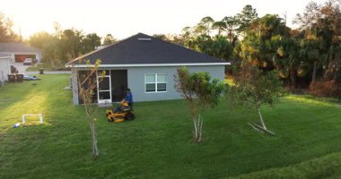 Florida banliyösünün arka bahçesinde çim biçme makinesi ile çim biçen profesyonel bir servis işçisi.