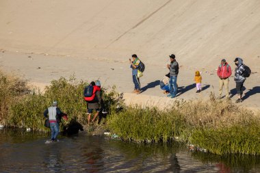 Juarez, Mexico, 12-21-2022: hundreds of migrants wait in front of the wall to be able to turn themselves in to the border patrol in American territory, to request humanitarian asylum.