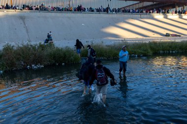 Juarez, Mexico, 12-21-2022: hundreds of migrants wait in front of the wall to be able to turn themselves in to the border patrol in American territory, to request humanitarian asylum.