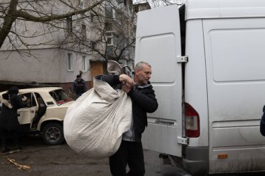 Bir adam, insani kriz ve kentsel sıkıntı belirtileri gösteren bir bölgedeki yardım çabalarına yardım etmek için minibüse büyük bir çanta dolusu erzak taşıyor.