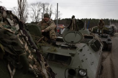 Kırsal bölgedeki zırhlı araçlara konuşlanmış askerler, çatışma bölgesini işaret ediyor.