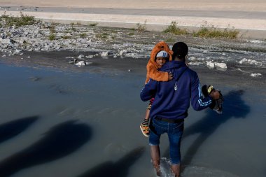 Üç kişi sığ bir nehirde yürüyor.