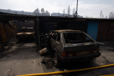 Yanmış araçlar, bir Rus saldırısının ardından hasarlı bir şehir garajında duruyor. Ukrayna 'da savaş, 2022.